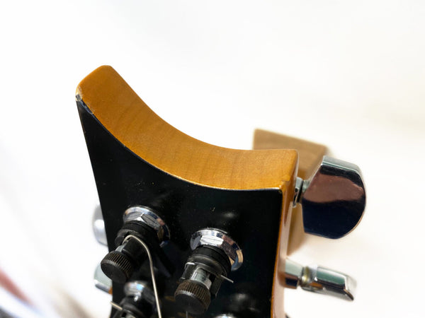 Close-up of guitar headstock with tuning pegs and wood finish edge detail, used for tuning strings on acoustic or electric guitars.