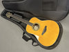 Yamaha acoustic guitar with natural wood finish in black padded soft case on gray surface