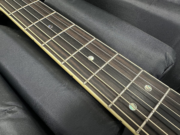 Close-up of acoustic guitar rosewood fretboard with metal frets and pearl dot inlays on black fabric background