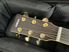 Close-up of Yamaha acoustic guitar headstock with gold tuning pegs inside padded black guitar case
