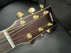 Close-up of Yamaha acoustic guitar headstock with gold tuning pegs and strings on black background