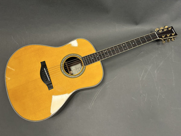 Yamaha acoustic guitar with natural wood finish, black bridge and tuning pegs, glossy top, and fretboard with dot inlays on gray background