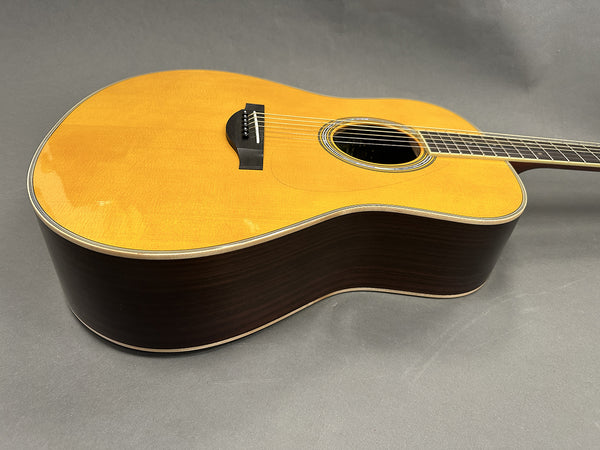 Acoustic guitar with natural spruce top and dark wood sides and back on gray background, close-up angled view of body and strings