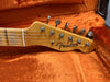 Close-up of Fender Telecaster guitar headstock with tuning pegs and strings in orange plush guitar case interior