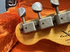 Close-up of vintage guitar tuning pegs on natural wood headstock with orange plush guitar case interior