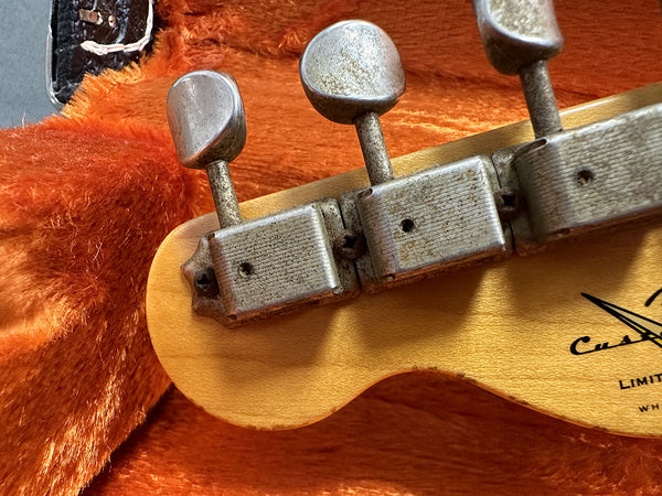 Close-up of vintage guitar tuning pegs on natural wood headstock with orange plush guitar case interior