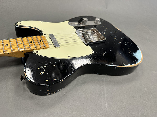 Black vintage-style electric guitar with white pickguard and worn finish, showing scratches and paint wear on body and maple neck with dot inlays, displayed on gray background.