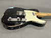 Black relic finish electric guitar with maple neck and fretboard, white pickguard, and chrome hardware on gray background