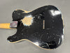 Black vintage electric guitar body with heavy wear and paint chipping showing natural wood underneath, six colorful string ferrules visible, and a neck plate with limited edition engraving