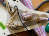 Close-up of Fender branded potentiometers and capacitors wiring inside electric guitar pickguard showing vintage-style electronics and solder connections