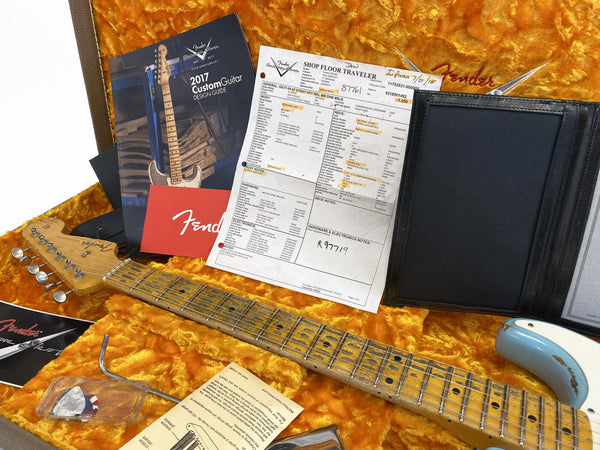 Fender Custom Shop guitar case interior with 2017 Custom Guitar Design Guide, build sheet, Fender guitar neck with relic finish, pick, tremolo arm, and documents on orange plush lining