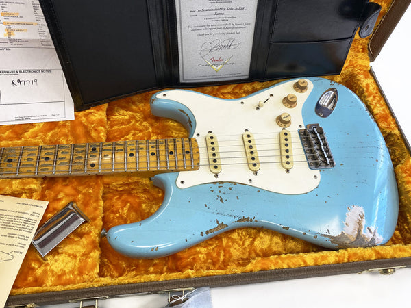 Fender 57 Stratocaster Hip Relic MB15 electric guitar in light blue finish with white pickguard, maple neck, vintage-style single-coil pickups, and aged hardware, displayed in orange plush-lined hard case with certificate and accessories.