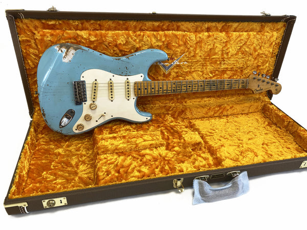 Vintage Fender Stratocaster electric guitar with worn light blue finish and maple fretboard displayed in plush yellow Fender hard case