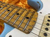 Close-up of worn vintage guitar fretboard and strings showing detailed wood grain and frets on electric guitar neck