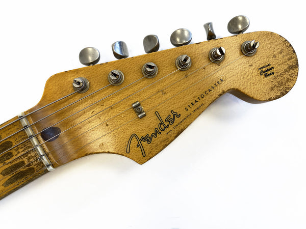 Close-up of vintage Fender Stratocaster guitar headstock with aged wood finish and silver tuning pegs on white background