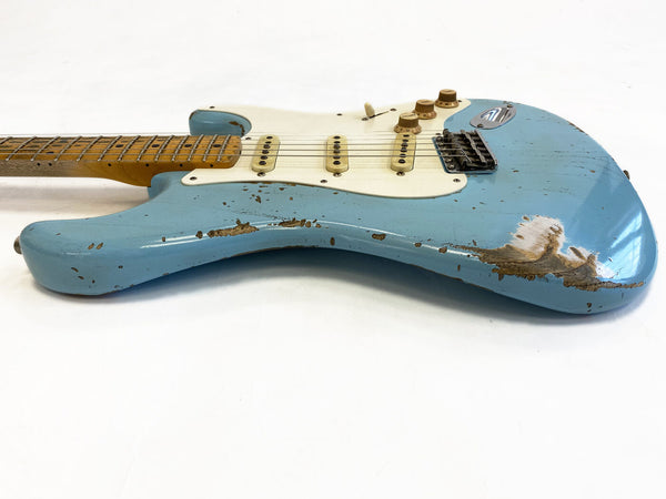 Vintage worn blue electric guitar with white pickguard and maple neck on white background, showing signs of heavy wear and paint chipping.