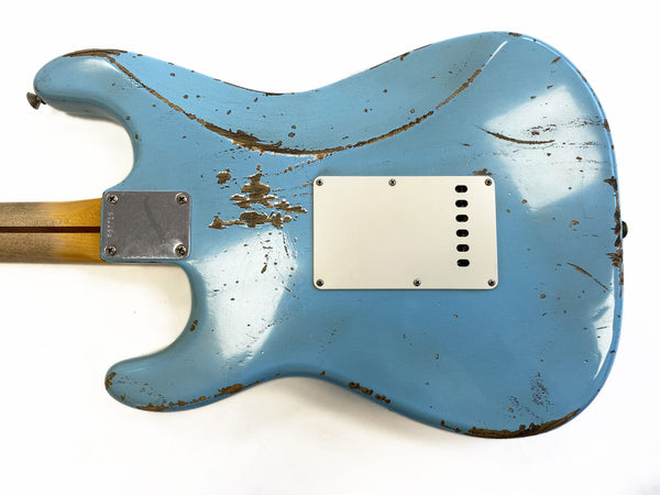 Back of vintage light blue electric guitar with heavy worn and distressed finish showing wood underneath, white plastic backplate, and maple neck with four-bolt metal neck plate against white background