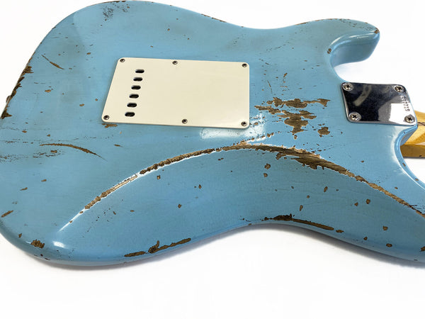 Close-up of worn light blue electric guitar body with relic finish, showing paint chips and scratches, white plastic backplate, and chrome neck plate screws