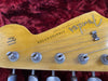 Close-up of vintage Fender Stratocaster guitar headstock with original contour body decal and tuning pegs on red velvet background