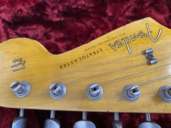 Close-up of vintage Fender Stratocaster guitar headstock with original contour body decal and tuning pegs on red velvet background