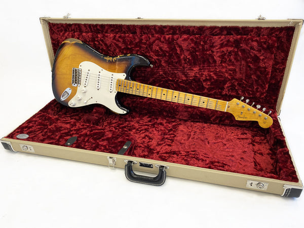 Vintage Fender Stratocaster electric guitar in sunburst finish with maple neck and rosewood fingerboard, displayed inside open vintage-style beige hard case with plush red interior lining.