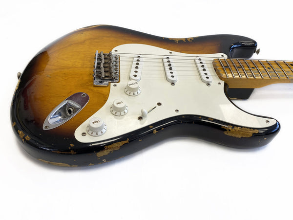 Vintage sunburst electric guitar with white pickguard and three single-coil pickups, showing worn and chipped finish on body and neck