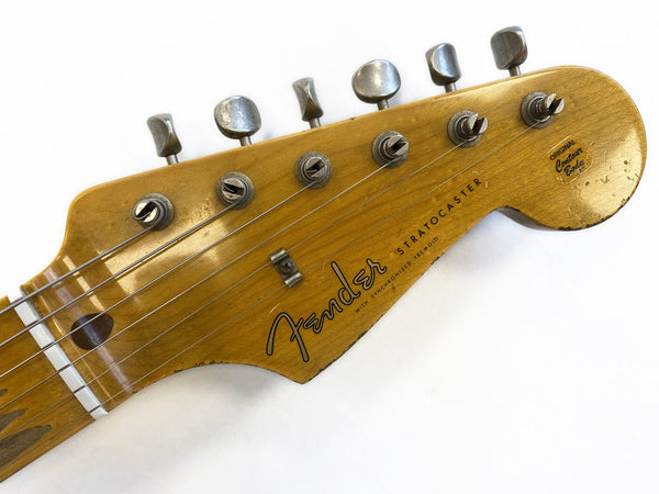 Close-up of vintage Fender Stratocaster guitar headstock with six tuning pegs, original finish, and strings on white background