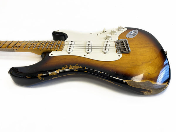 Vintage sunburst electric guitar with white pickguard and distressed finish on body and neck, Fender Stratocaster style with three single-coil pickups, volume and tone control knobs on white background