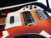 Close-up of vintage red electric bass guitar with white pickguard, chrome pickups, and black control knobs inside a black padded guitar case
