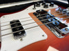 Close-up of electric guitar pickups, strings, control knobs, and white pickguard on a red wood grain guitar body in case