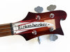 Close-up of vintage Rickenbacker bass guitar headstock with tuning pegs and red strings on white background