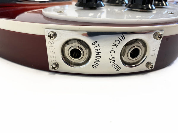 Close-up of vintage electric guitar dual output jack plate with "Rick-O-Sound" and "Standard" labels on red body with white binding and control knobs.