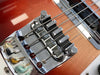 Close-up of chrome bridge and metal saddles on sunburst electric bass guitar with four strings and pickups