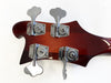 Close-up of Rickenbacker bass guitar headstock in cherry sunburst finish with four chrome tuning pegs against white background