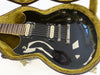 Black electric guitar with dual humbucker pickups and chrome hardware in a plush green-lined guitar case