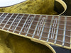 Close-up of guitar fretboard with rectangular inlays and metal strings on a wooden neck, guitar resting on yellow plush interior case lining