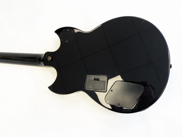 Back view of black electric guitar body showing battery compartment and control cavity cover against white background