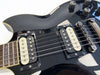 Close-up of black electric guitar body featuring dual EMG humbucker pickups, metal bridge, and control knobs with cream binding and rosewood fretboard
