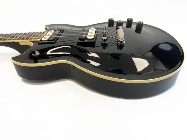Black electric guitar with cream binding, two humbucker pickups, four control knobs, and a tune-o-matic bridge on white background