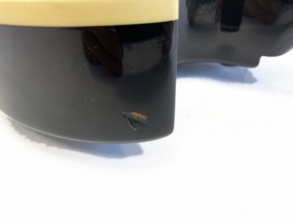 Close-up of a black guitar body corner with visible paint damage and wood exposed near the edge.