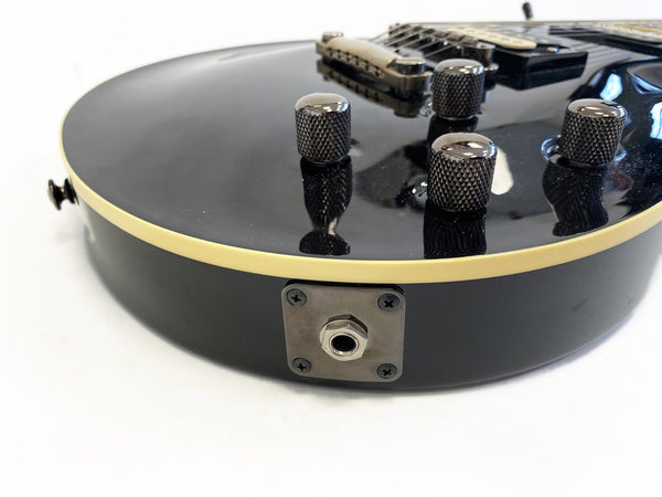 Close-up of black electric guitar body with cream binding, metal control knobs, and input jack plate, ideal for rock and blues musicians