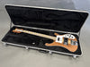 Electric bass guitar with natural wood finish, maple fretboard, and chrome hardware in a black plush-lined hard case
