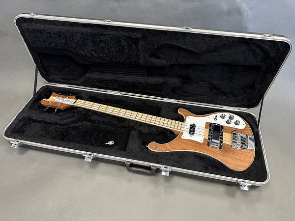 Electric bass guitar with natural wood finish, maple fretboard, and chrome hardware in a black plush-lined hard case