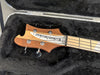 Rick Taylor electric bass guitar headstock with tuning pegs and distinctive wood grain resting in black plush guitar case