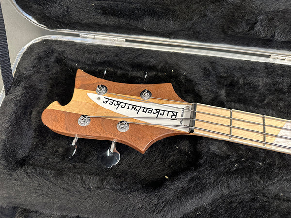 Rick Taylor electric bass guitar headstock with tuning pegs and distinctive wood grain resting in black plush guitar case