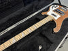 Electric bass guitar with natural wood finish and white pickguard in black plush-lined hard case with storage compartment and key inside