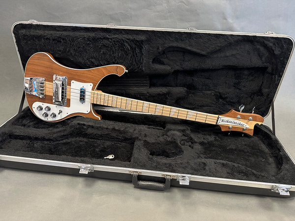 Rickenbacker bass guitar with wooden finish in black plush-lined hard case on gray background