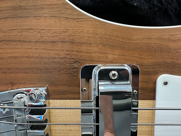 Close-up of chrome bridge and pickup on natural wood finish electric guitar body with steel strings and white pickguard