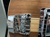 Close-up of chrome bridge and pickups on natural wood finish electric bass guitar with four strings and black strap