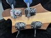 Close-up of chrome Rickenbacker tuning pegs on the back of a two-tone wooden guitar headstock in a black guitar case interior